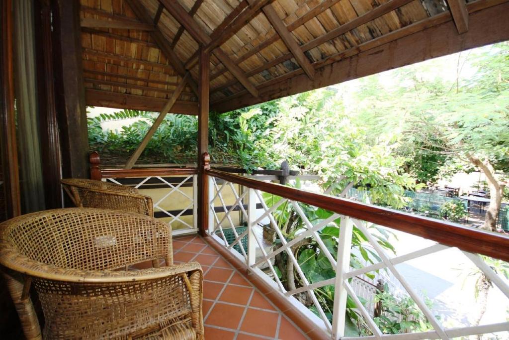 a balcony with wicker chairs and a view of trees at Sala Prabang Hotel in Luang Prabang