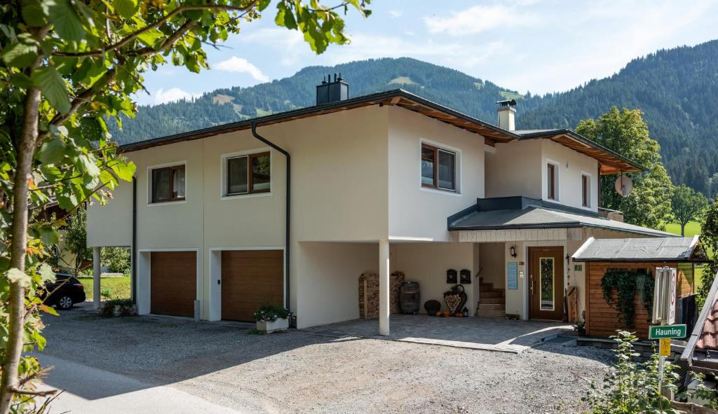 une maison avec un garage et des montagnes en arrière-plan dans l'établissement Appartement Annabella, à Söll