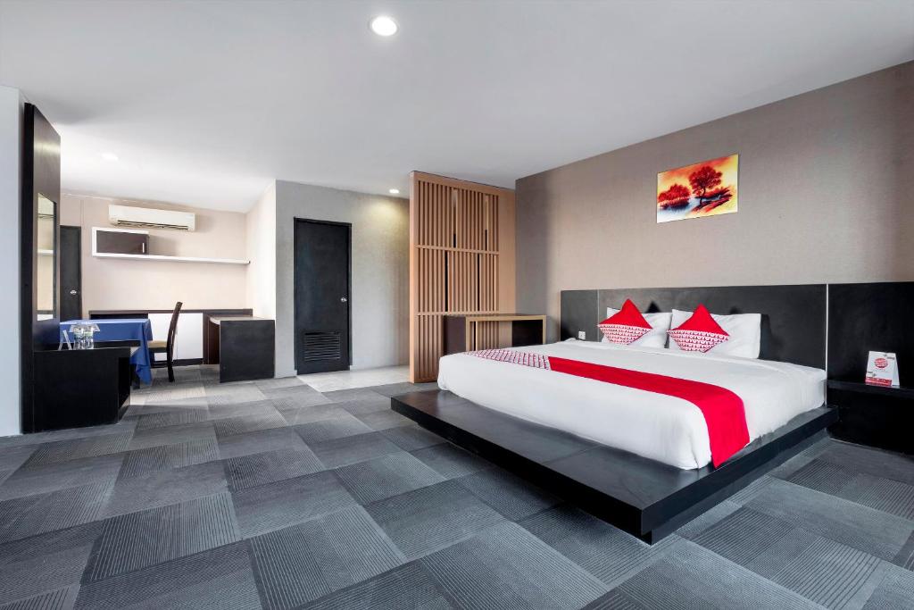 a large bedroom with a large white bed with red pillows at SUPER OYO Capital O 472 Hotel Asyra in Makassar