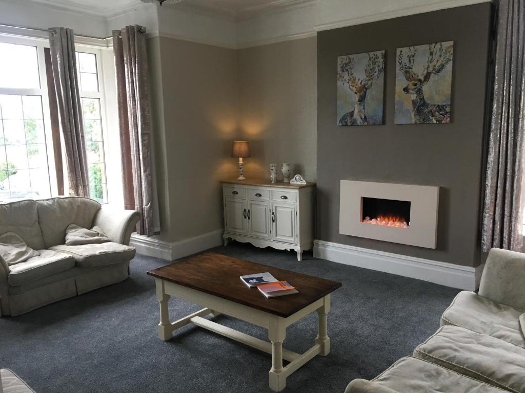 a living room with a coffee table and a fireplace at Holly Trees Hotel in Alsager