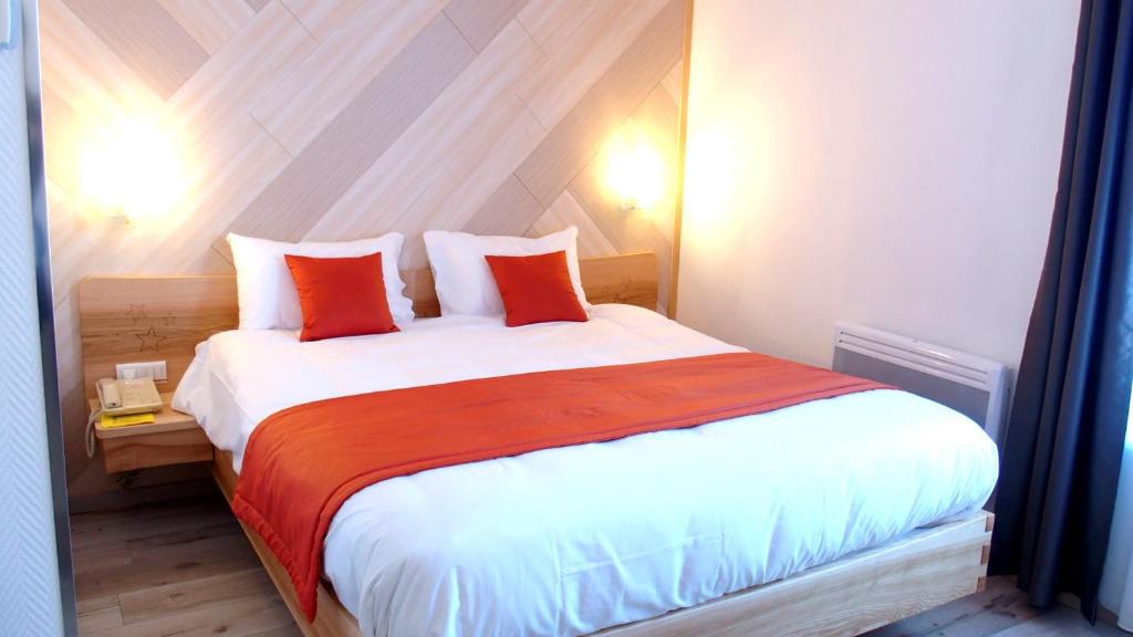 ein Schlafzimmer mit einem großen weißen Bett mit roten Kissen in der Unterkunft Hostellerie de l'Étoile in Wasselonne