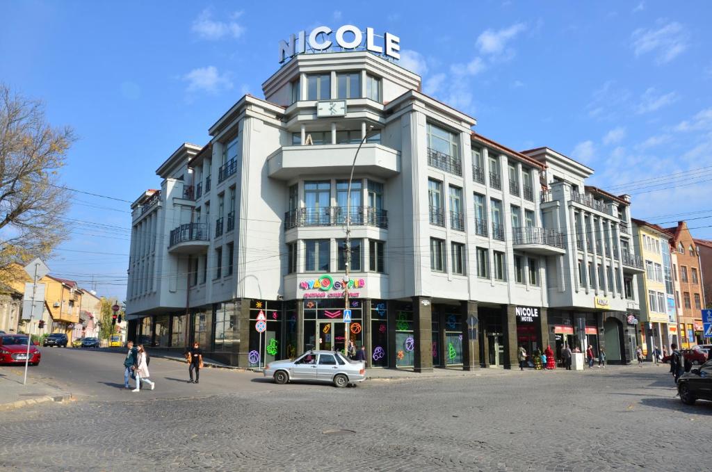 um grande edifício com um carro estacionado em frente em Nicole em Uzhhorod