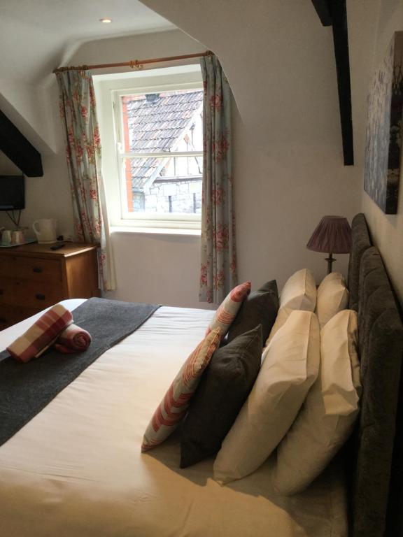 a bedroom with a bed with pillows and a window at Plume of Feathers in Blagdon