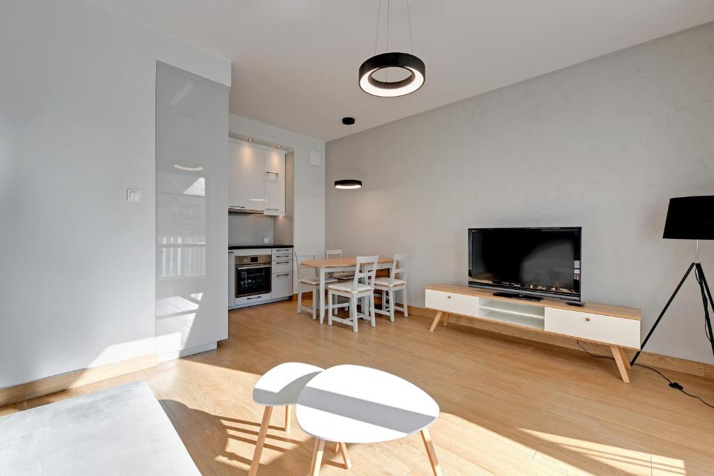 a living room with a television and a table and chairs at Holiday Apartment near the Sea - free private parking in Gdańsk
