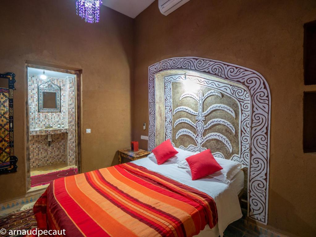 una camera da letto con un grande letto con cuscini rossi di Dar M'hamid a M'Hamid