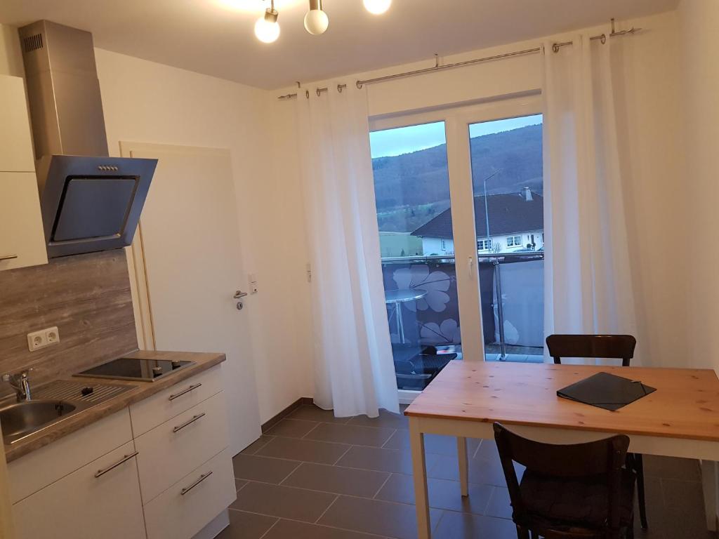 cocina con mesa con sillas y ventana en FeWo Louise, en Kinderbeuern
