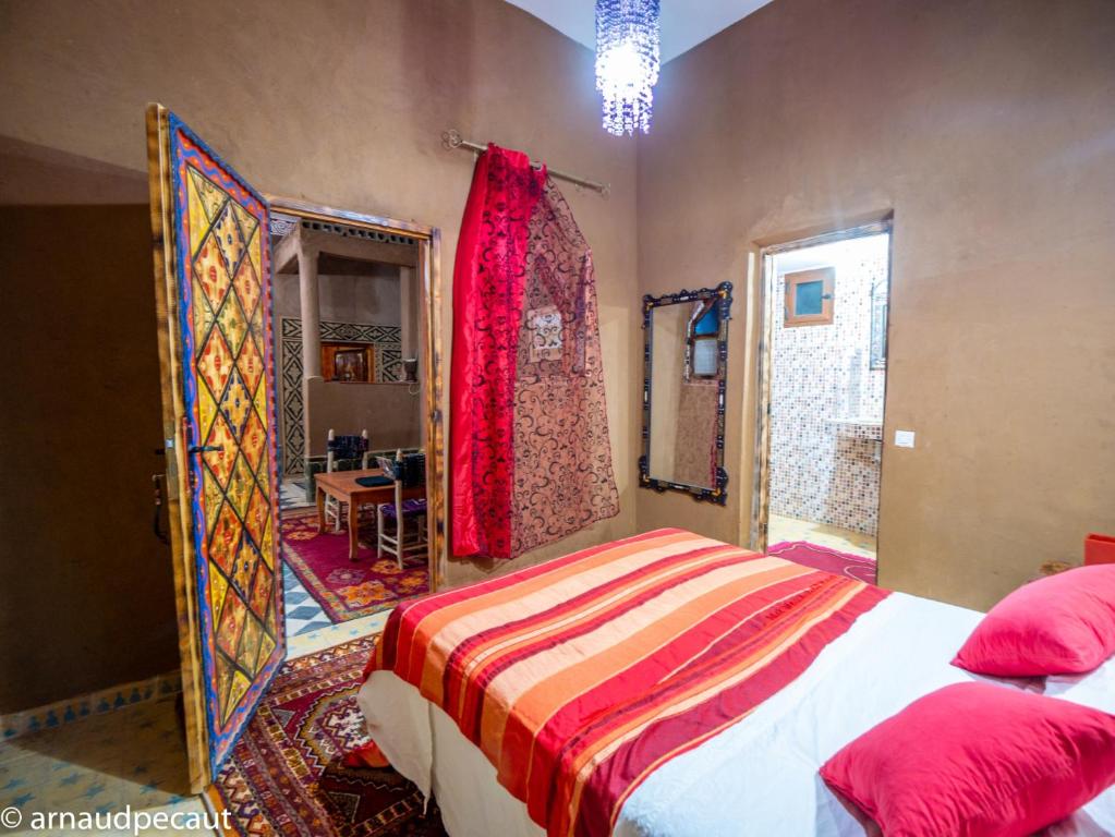 Un dormitorio con una cama con almohadas rojas y una ventana en Dar M'hamid, en Mhamid