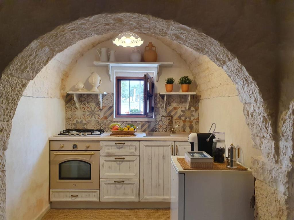 a kitchen with an archway with a sink and a stove at I Trulli di Nonna Maria in Alberobello