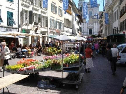 a group of people walking around a market with flowers at Hotel Ambassador in Solothurn