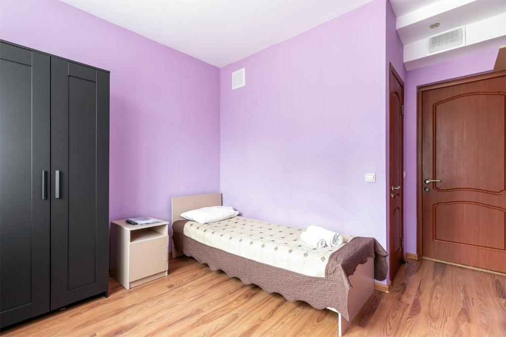 1 dormitorio con cama y pared púrpura en Cheremushki Hotel en Moscú