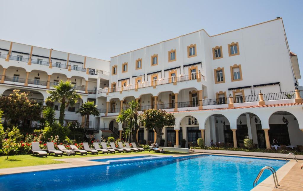 um hotel com piscina em frente a um edifício em El Minzah Hotel em Tânger
