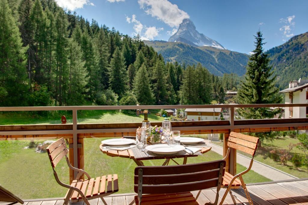 a table and chairs on a deck with a view of a mountain at Chalet Altesse - Premium Apartments in Zermatt