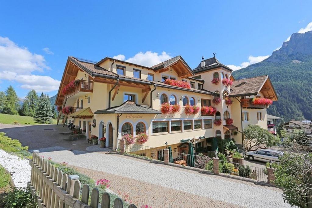 ein großes Haus mit Blumen auf der Seite in der Unterkunft MyTime Hotels la Grotta in Vigo di Fassa