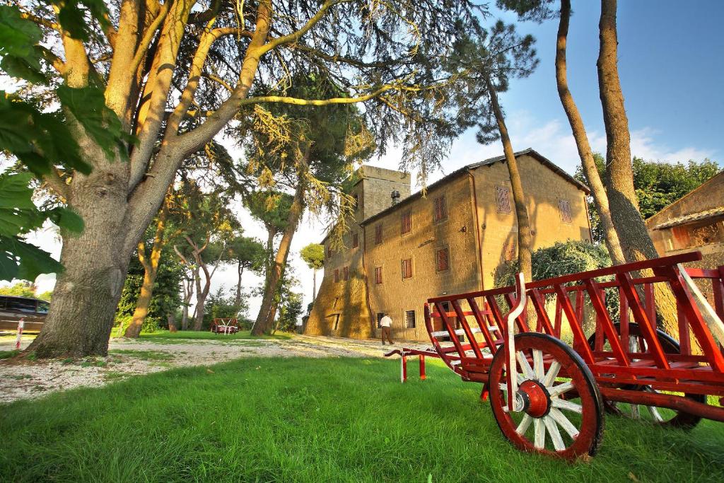 un banc rouge assis dans l'herbe à côté d'un bâtiment dans l'établissement Antico Borgo La Commenda, à Montefiascone