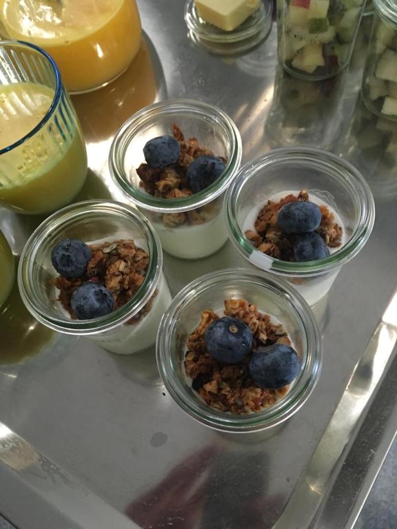 four bowls of food on a counter with blueberries and granola at Samsted in Middelfart