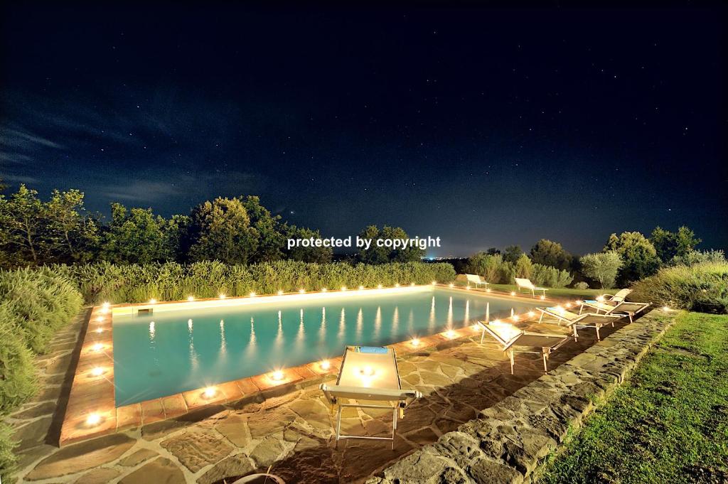 una piscina con sillas y luces en un patio en Luxury Stone Villa Salt Water Pool, en Rapolano Terme