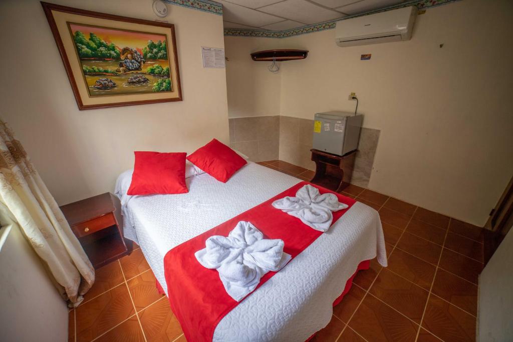 Schlafzimmer mit einem Bett mit roter und weißer Bettwäsche und Bögen in der Unterkunft Hostal Gladismar in Puerto Villamil