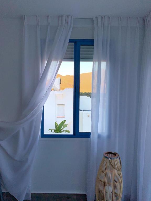 a window with white curtains and a vase in a room at Alojamientos 4nudos in San José