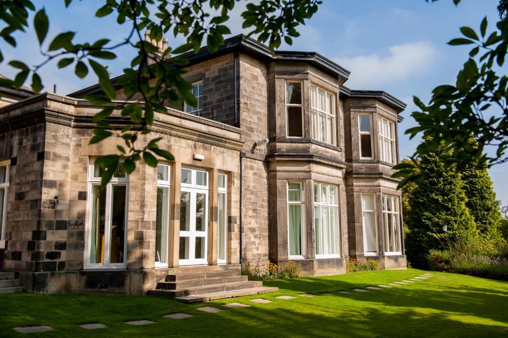 une ancienne maison en pierre avec une cour herbeuse dans l'établissement Halifax Hall, à Sheffield