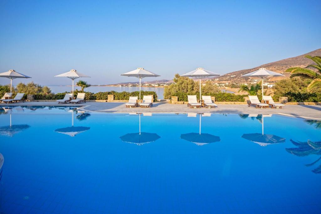 a large blue swimming pool with chairs and umbrellas at Poseidon of Paros Hotel & Spa in Chrissi Akti