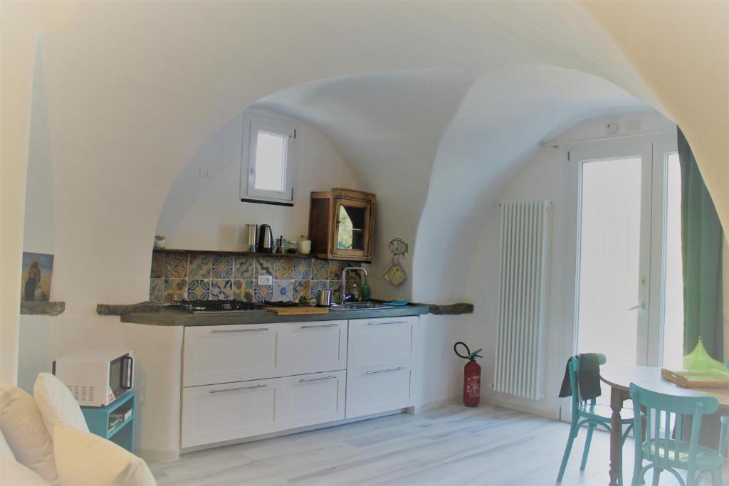 una cucina con armadi bianchi, tavolo e finestra di ANTICA CASA DEL CANTO Iara a Calice Ligure