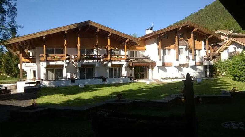 a large building with a lawn in front of it at Residenza e Appartamenti Le Colonnine in Pozza di Fassa