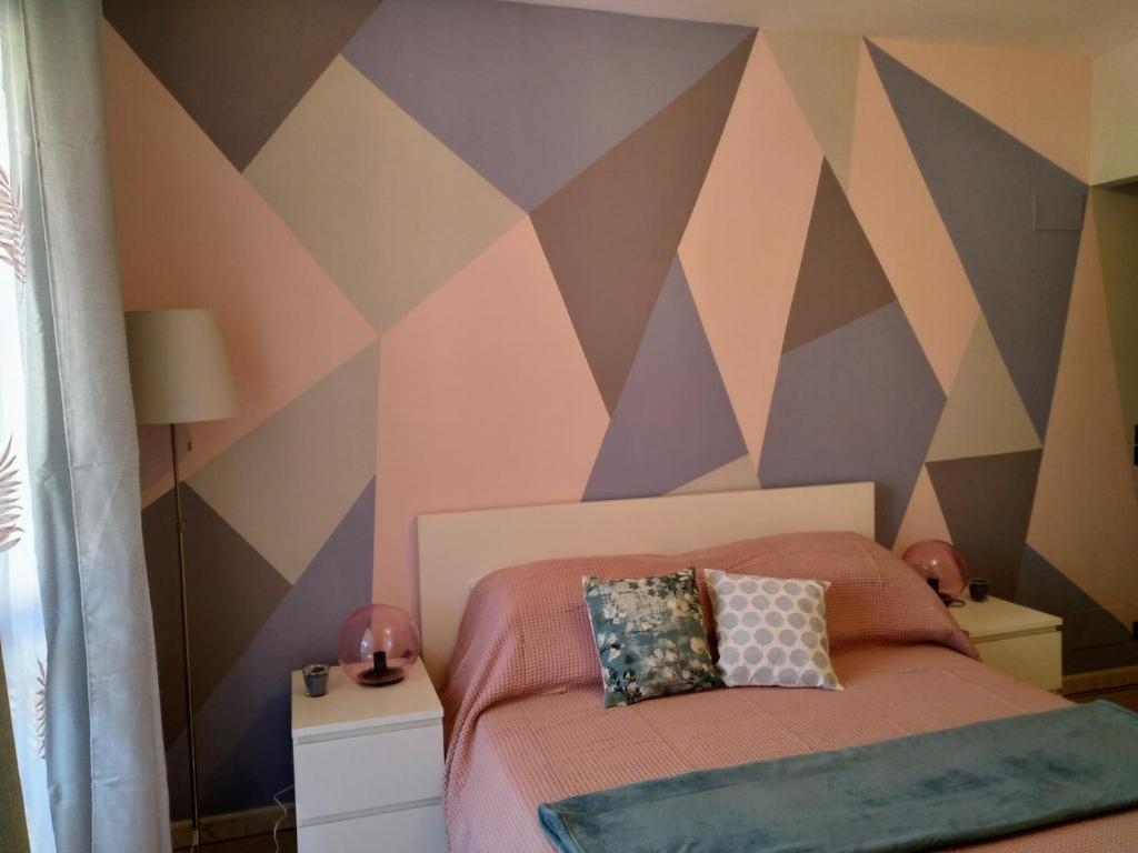 a bedroom with a bed with a geometric accent wall at POST A POST in Alba