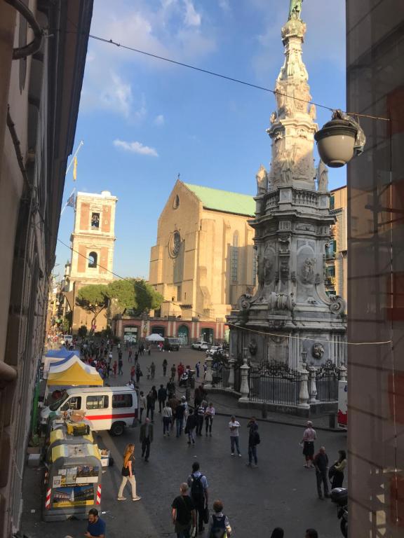 una folla di persone che camminano per strada con una statua di Cisterna’s house a Napoli