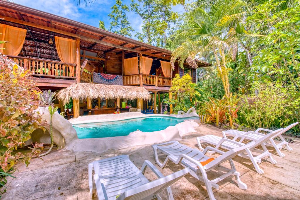 
a beach area with a pool, chairs, and a table at Caribe Town Bungalows in Puerto Viejo
