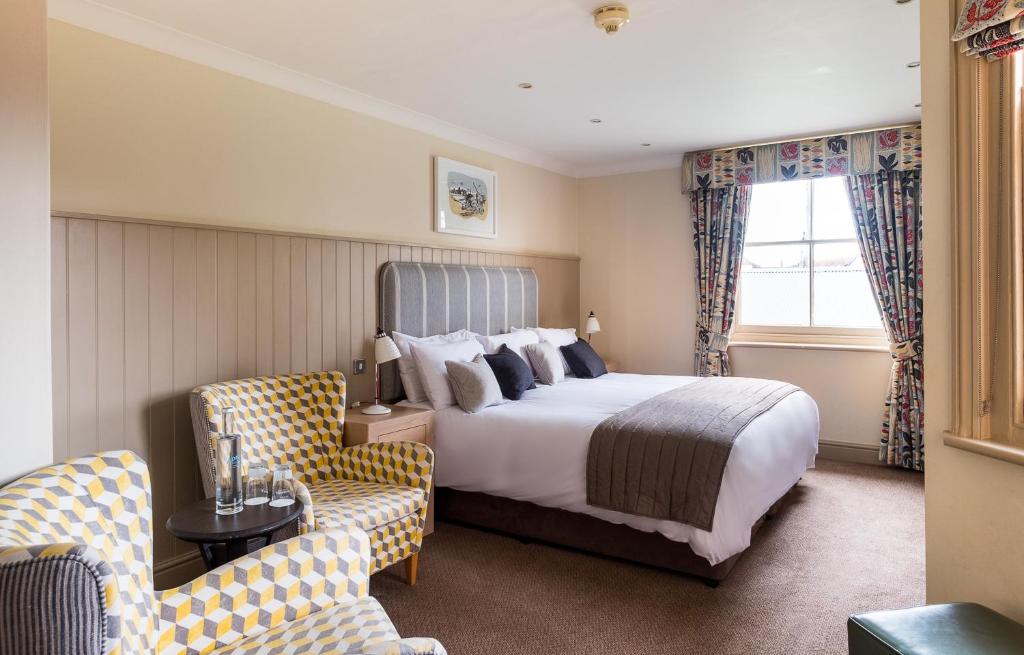 a hotel room with a bed and two chairs at Crown Hotel in Southwold