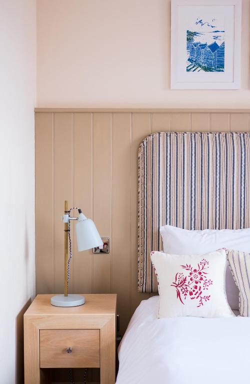a bedroom with a bed and a lamp on a night stand at Crown Hotel in Southwold