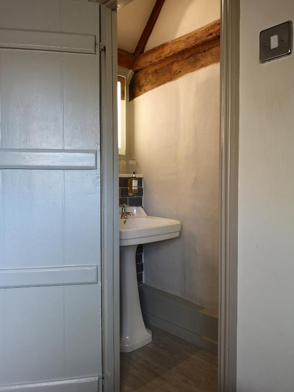 a white bathroom with a sink and a mirror at Crown Hotel in Southwold