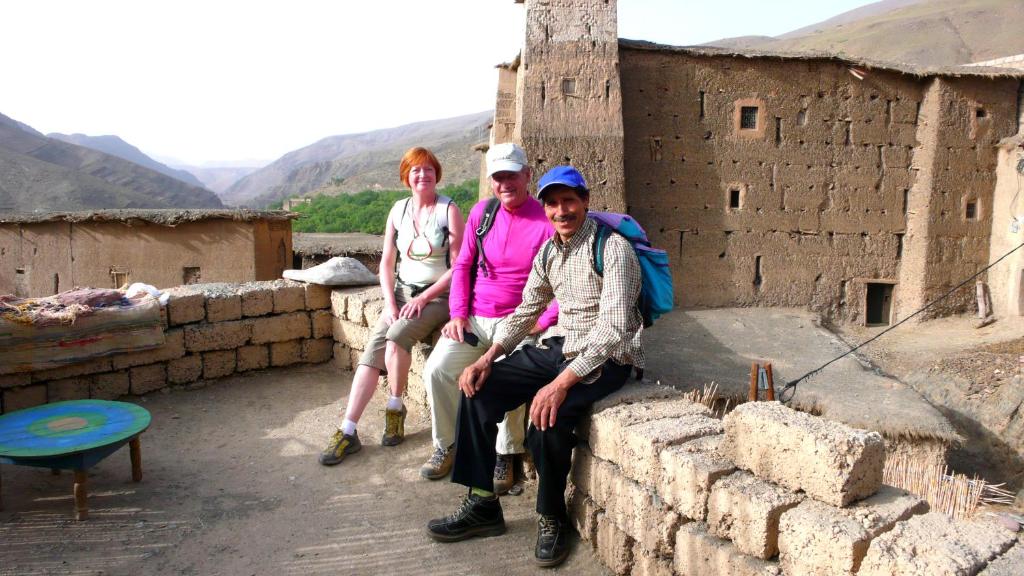 eine Gruppe von drei Personen, die an einer Wand sitzen in der Unterkunft Gite Chez Brahim in Skoura