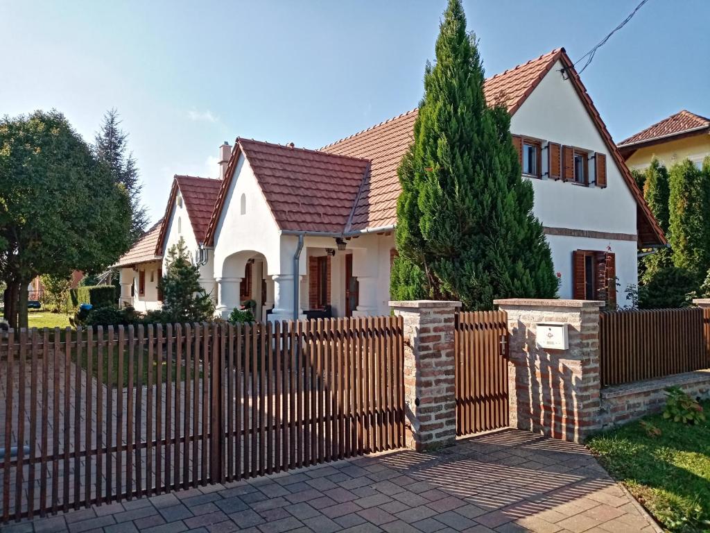 a fence in front of a white house at Négy Évszak Apartmanház in Zalakaros