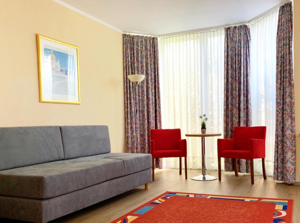 ハーナウ・アム・マインにあるTurm Hotel Hanauのリビングルーム(ソファ、赤い椅子付)