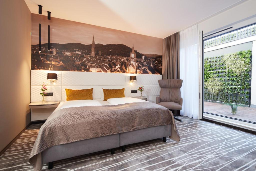 um quarto com uma cama grande e uma janela grande em Boutiquehotel am Stadtgarten em Friburgo em Brisgóvia