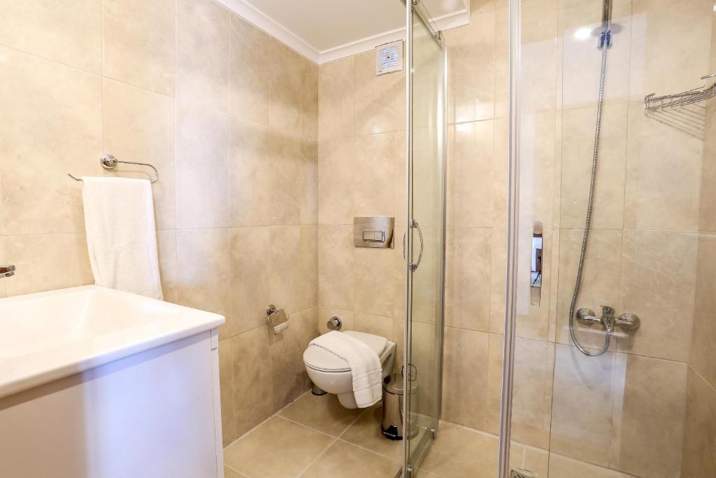 a bathroom with a shower and a toilet and a sink at Medimar Hotel in Kaş