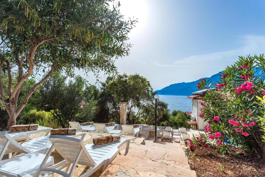 a group of white chairs and a tree and water at Medimar Hotel in Kaş