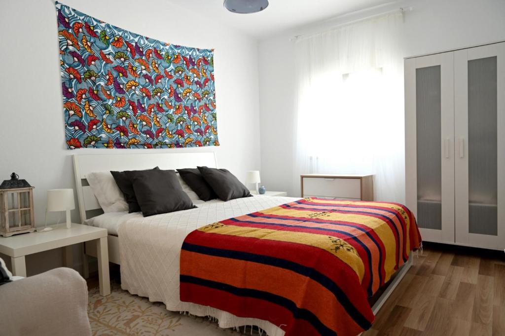 1 dormitorio con 1 cama grande con una manta colorida en Casa dos Clérigos, en Alcácer do Sal