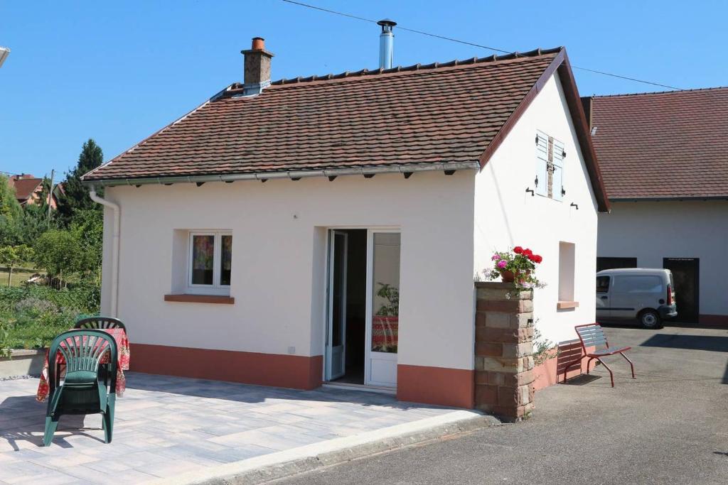 una piccola casa bianca con due sedie davanti di Gîte chez Claude & Jacqueline a Neuwiller-lès-Saverne