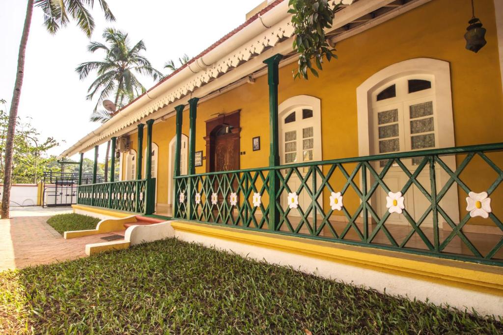 a yellow house with a green fence at Prazeres Boutique Hotel in Panaji