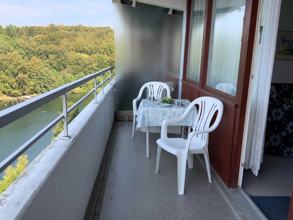 un balcón con 2 sillas blancas y una mesa. en App_ an der Seepromenade _ Mittels, en Malente