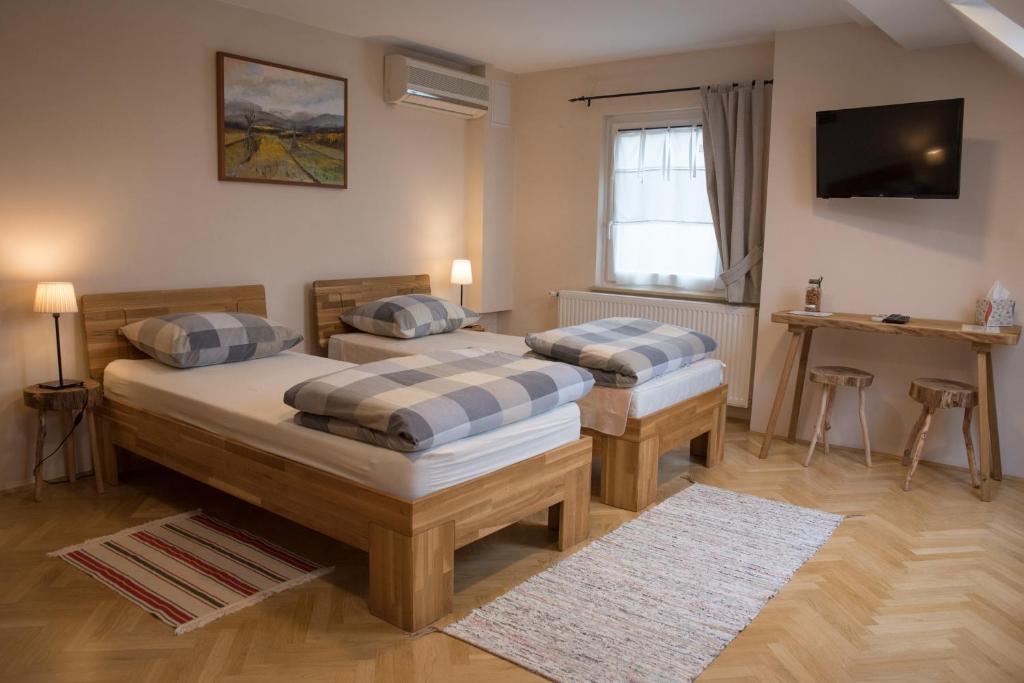 um quarto com duas camas e uma televisão na parede em Bed & Breakfast Dvorec em Petrovče