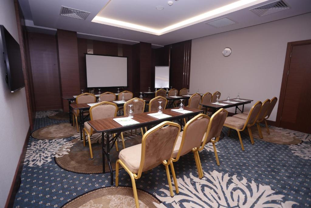 a conference room with tables and chairs and a screen at Holiday Inn Ankara - Cukurambar, an IHG Hotel in Ankara