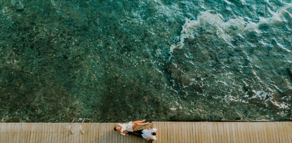 una persona de pie en una pared mirando al océano en Pefkaki Boutique Hotel Loutraki, en Loutraki