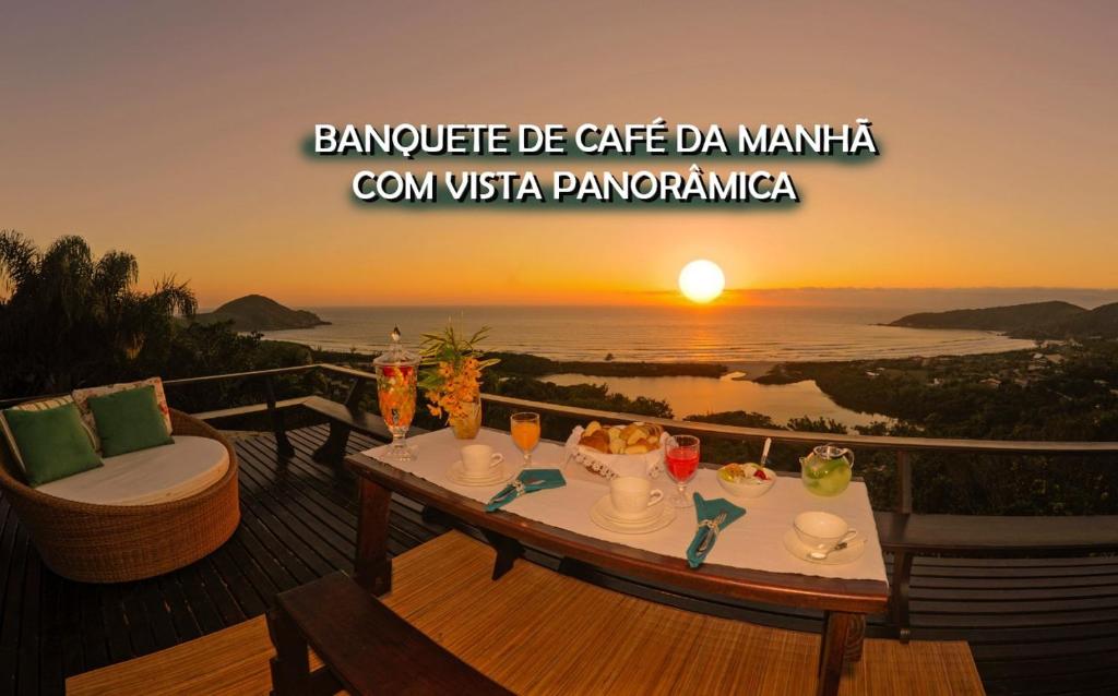 a table on a deck with the sunset in the background at Pousada Morada dos Sisais in Praia do Rosa