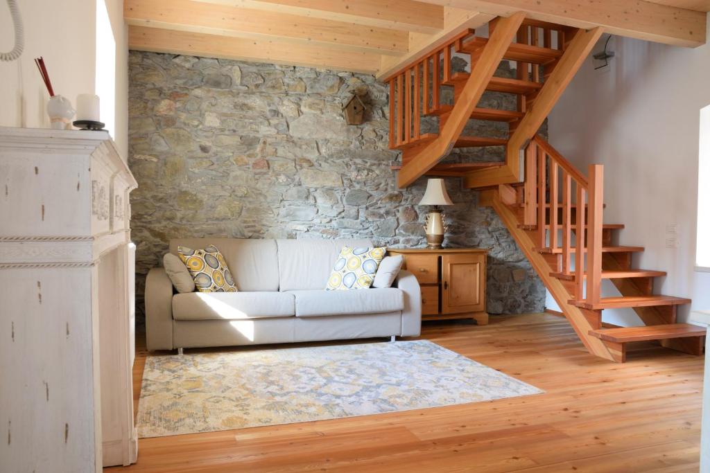 a living room with a white couch and a stone wall at Coccole nel fienile in Levico Terme
