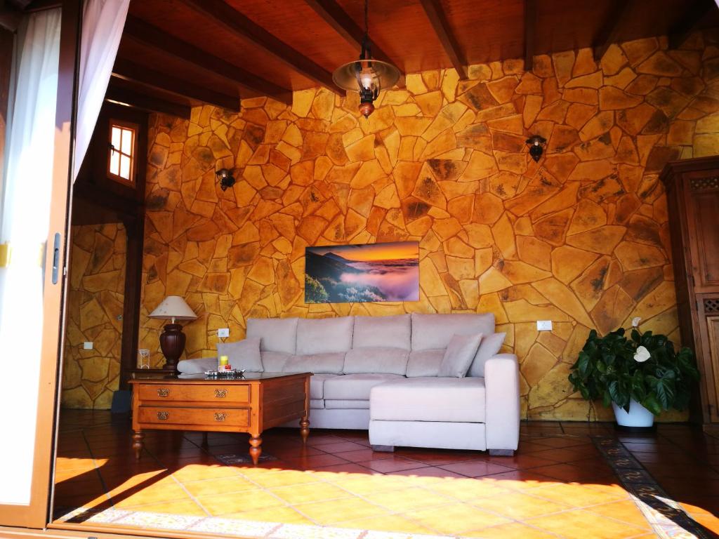 a living room with a couch and a stone wall at Camino Real in Barranco Hondo
