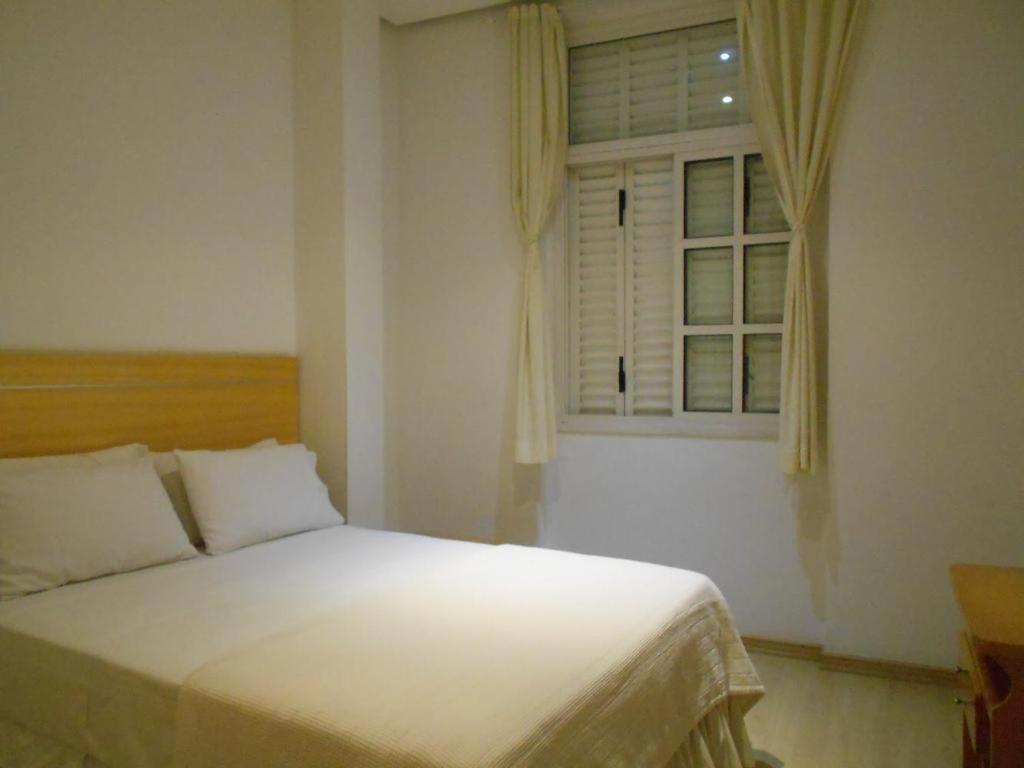 1 dormitorio con cama blanca y ventana en South beach residence copacabana, en Río de Janeiro