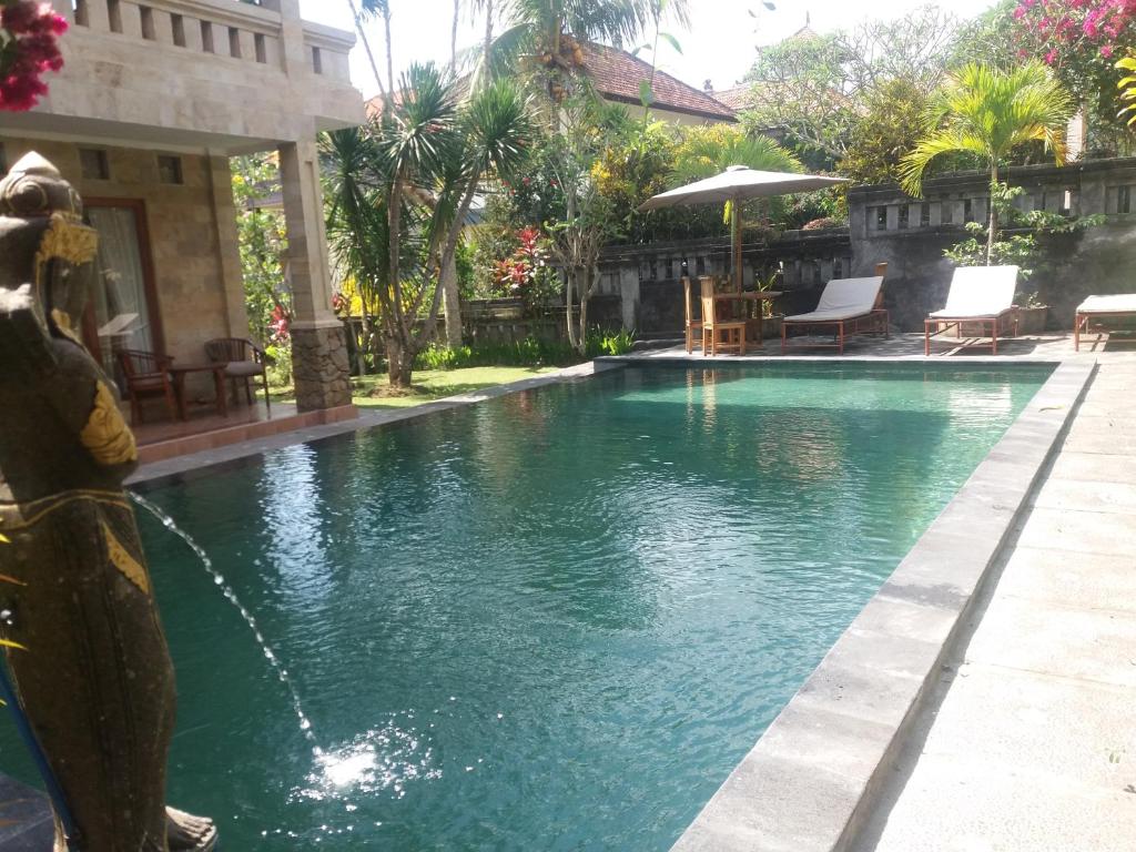 a swimming pool with a fountain in a yard at Dewi Ayu Accommodation in Ubud